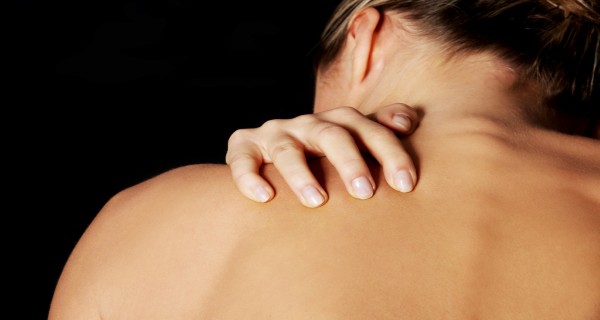 Nude, topless woman, scratching her neck. back view. On black ba